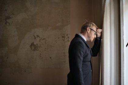 Desperate evicted male entrepreneur standing near window